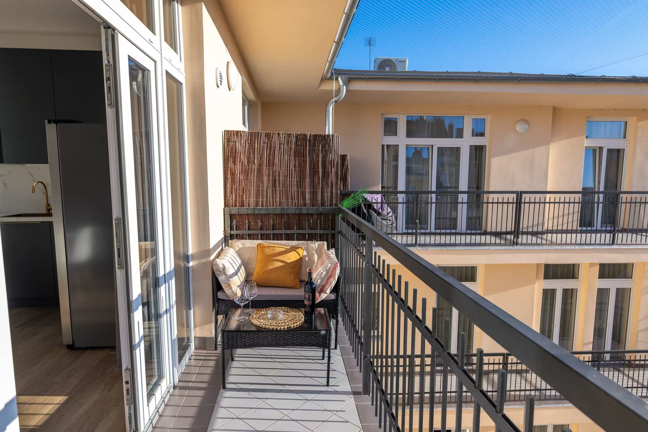 Terraza del estudio de Málaga antes del retoque, con sofá, mesa baja y salida a la cocina